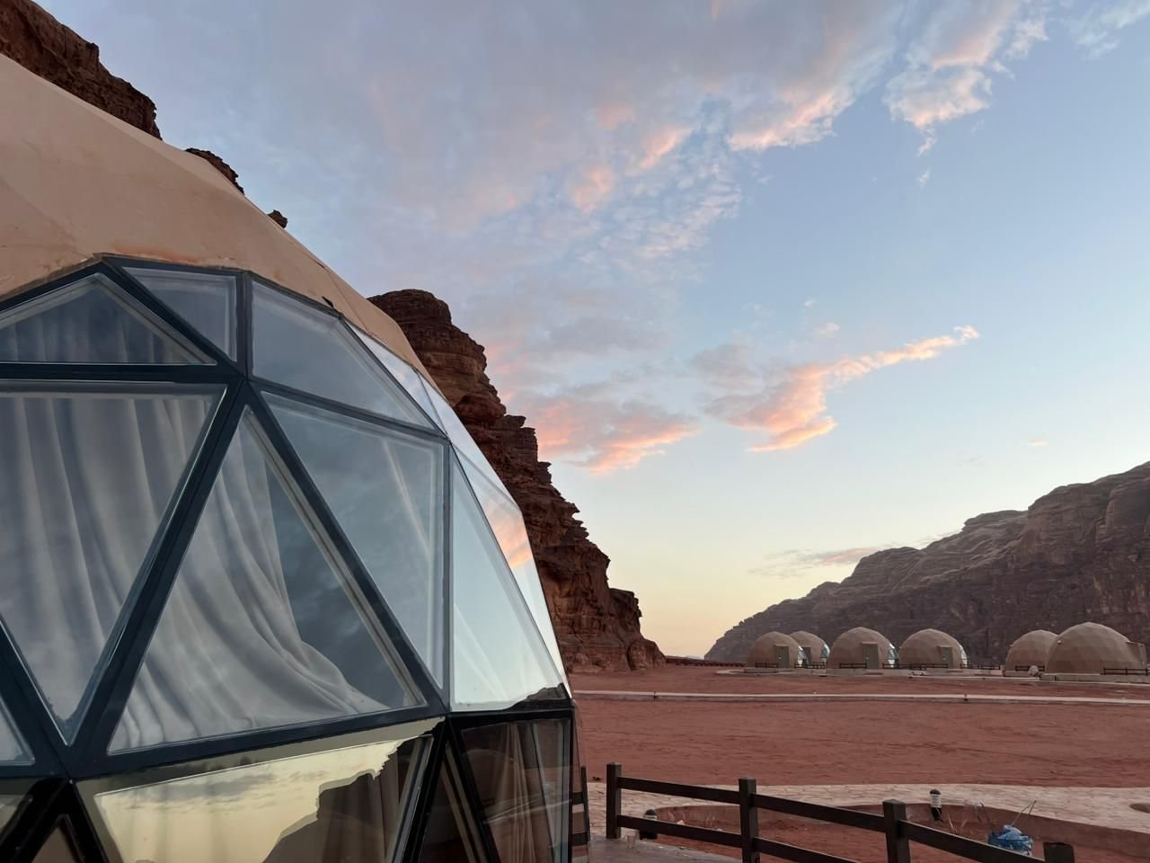 A glass dome at sunset, the camp's domes under the Wadi Rum cliffs