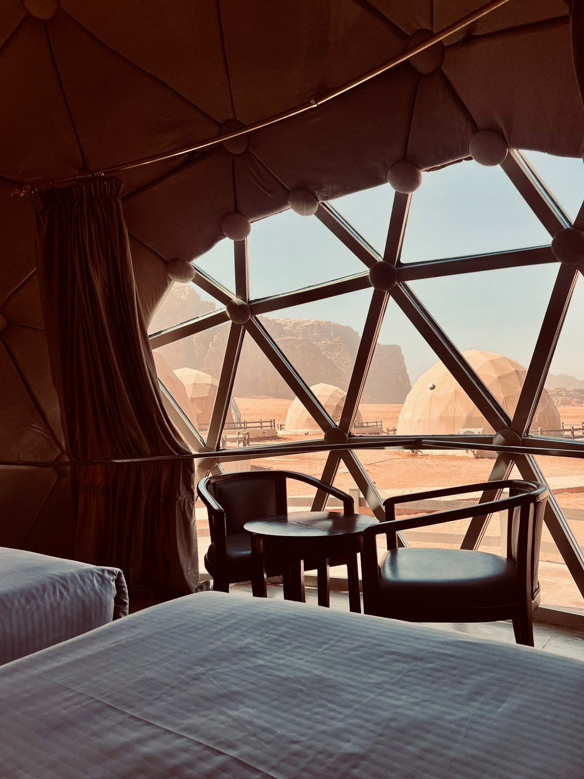 Inside a dome, looking out through the glass to the camp and cliffs
