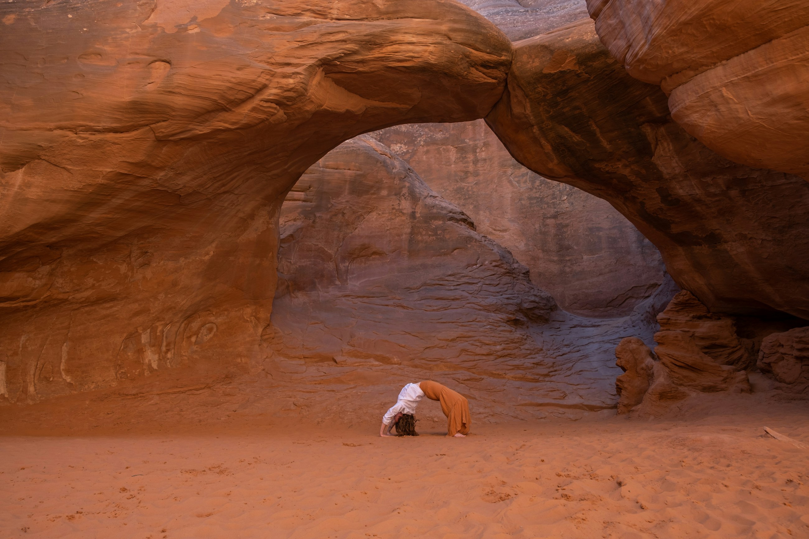 Yoga under a red sandstone arch in the desert